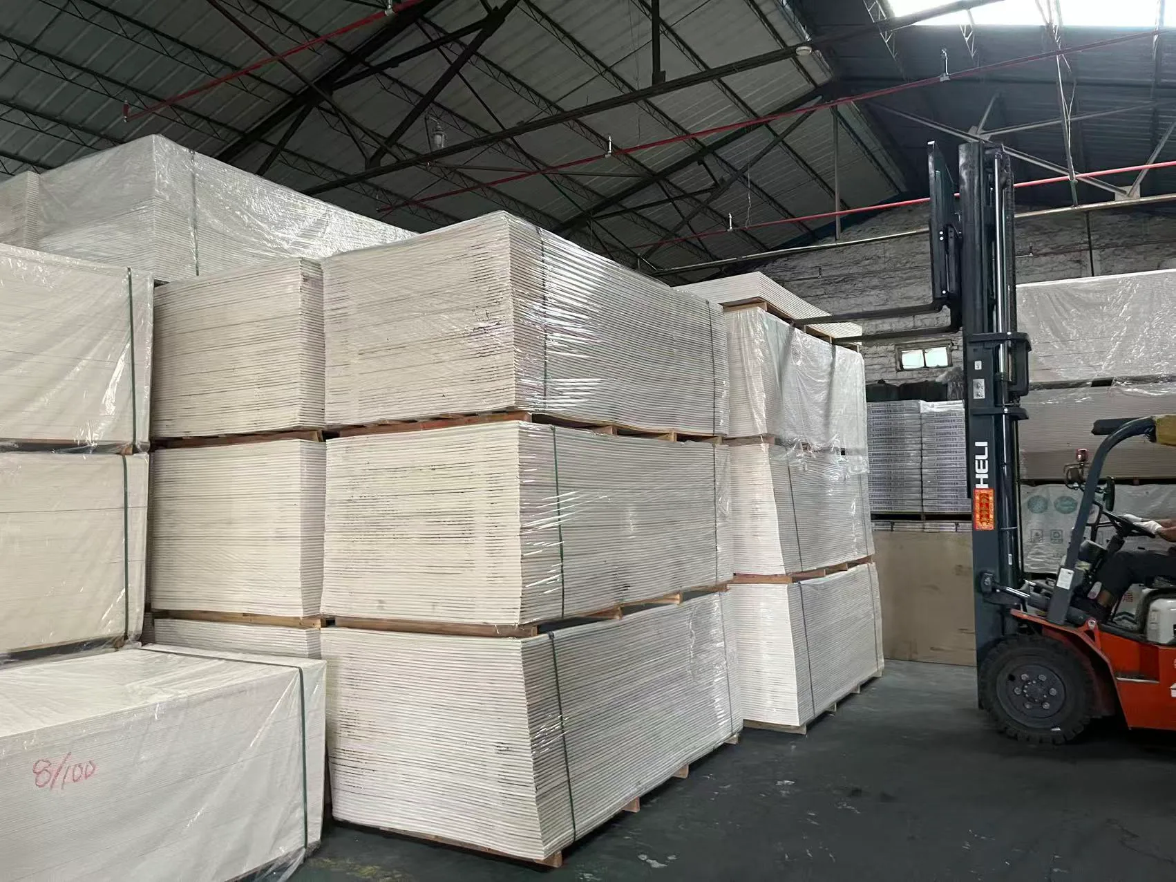 Forklift beside wrapped stacks of finished acoustic panels in the factory warehouse